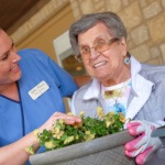 Tiffin House resident Ruth helps Tracy plant flowers on the back porch-min